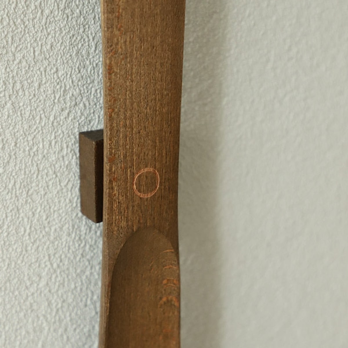 Närbild på det magnetiska väggfästet i trä och den infällda magneten på skohornets baksida