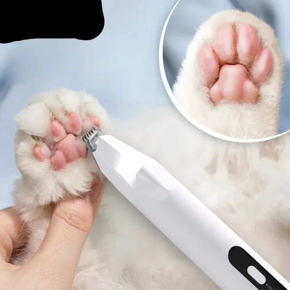 Tasstrimmer använd på en kattass, med närbild på knivhuvudet mellan trampdynorna